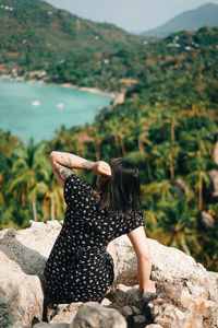 Rear view of woman sitting on rock