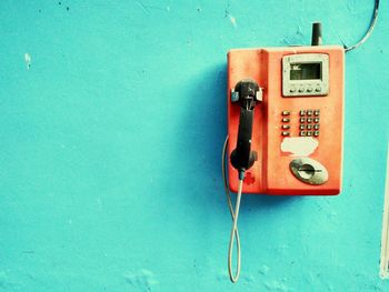 Close-up of landline phone mounted on blue wall