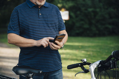 Midsection of senior man using mobile phone in park