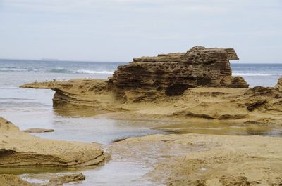 Rock formation on beach against sky