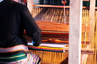 Midsection of woman working with loom in workshop