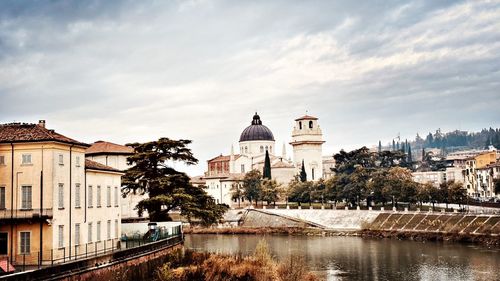 Buildings by river against sky