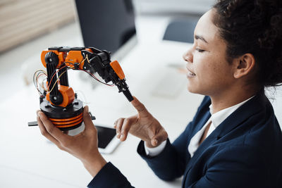 Smiling woman touching robotic arm sitting at desk