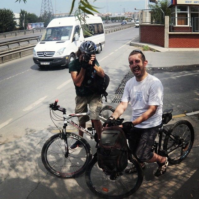 transportation, mode of transport, land vehicle, lifestyles, casual clothing, full length, leisure activity, bicycle, person, street, young adult, car, portrait, looking at camera, building exterior, young men, riding