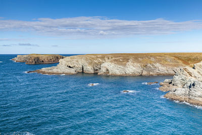 Rocks by sea against blue sky