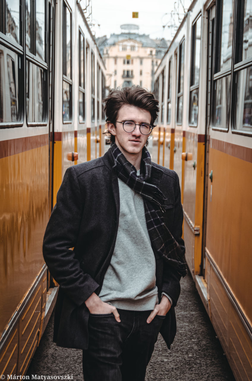 PORTRAIT OF MAN STANDING ON TRAIN AT RAILROAD STATION