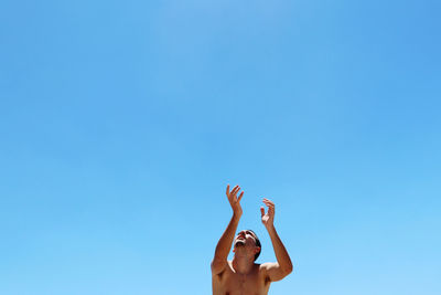 Young man looking above with open hands