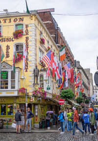 People walking on street against buildings in city