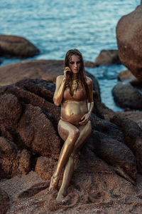 Pregnant women in golden sequins on the background of the ocean