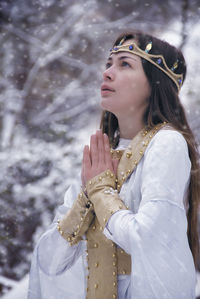 Woman in costume praying against trees