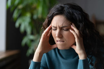 Unhappy stressed woman suffering from headache at workplace, anxious female having pain in head