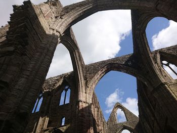 Low angle view of old ruin building against cloudy sky