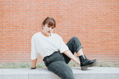 Portrait of woman standing against brick wall