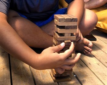 Midsection of man holding stack of wood