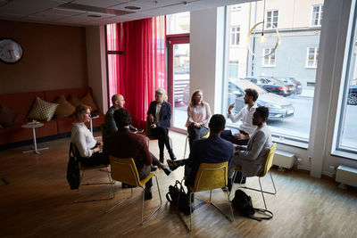 High angle view of male and female entrepreneurs sitting in circle at workplace