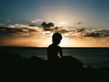 Silhouette man on beach against sky during sunset