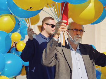 Low angle view of people holding multi colored balloons