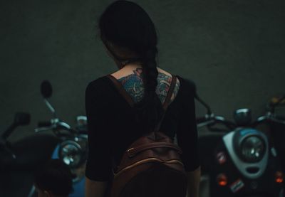 Rear view of woman with tattoo on her back carrying backpack