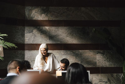 Smiling female financial advisor discussing with colleagues at law office