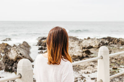 Rear view of woman looking at sea shore against sky