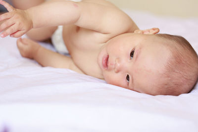 Portrait of cute baby lying on bed