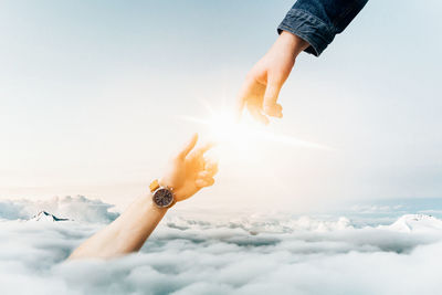 Digital composite image of hands touching sun
