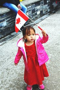 Full length of cute girl holding pink while standing outdoors