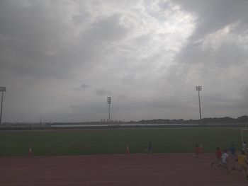 People playing soccer on field against sky