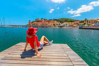 Full length of man sitting on pier against sky