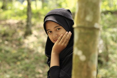 Portrait of beautiful young woman against trees