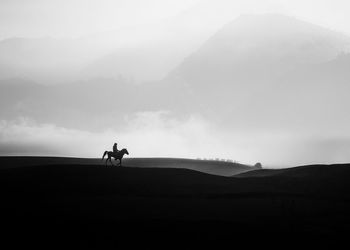 Silhouette men on mountain against sky