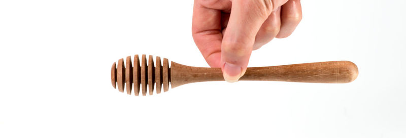 Close-up of hand holding metal against white background