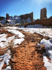 Rock formations on snow covered land against sky