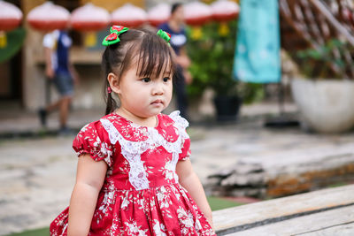 Girl looking away while standing against blurred background