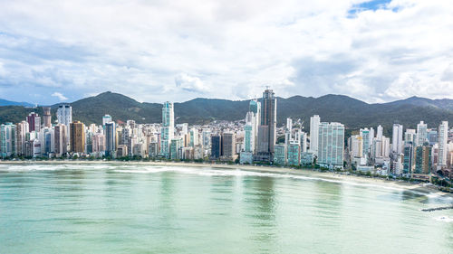 Sea by city buildings against sky