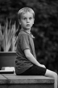 Boy looking away while sitting on wood