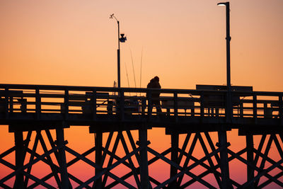 Silhouette man standing on pier against sky during sunset