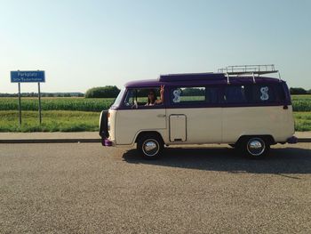 Woman in van showing peace sign on road