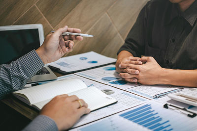 Midsection of man holding paper while sitting on table