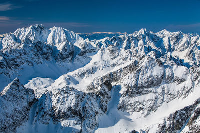 Scenic view of snowcapped mountains against blue sky