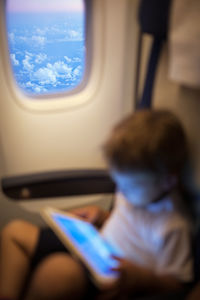 Boy using digital tablet while sitting in airplane 