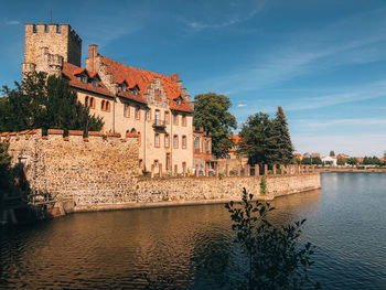 Buildings by river against sky