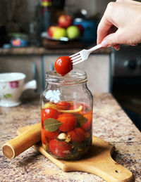 Close-up of hand holding glass jar on table