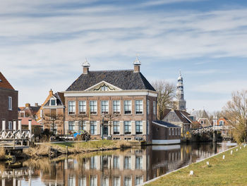 Buildings by river against sky