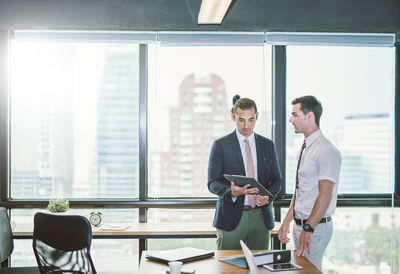 Young businessmen discussing over file at office