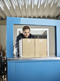 Worker watching machine closing packages
