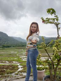 Portrait of a smiling young woman standing on landscape