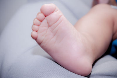 Low section of baby lying on bed