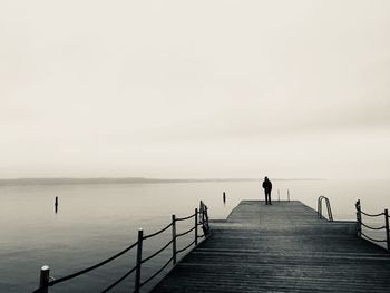 Man standing on railing against sea