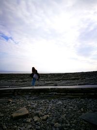 Woman standing on footpath against sky